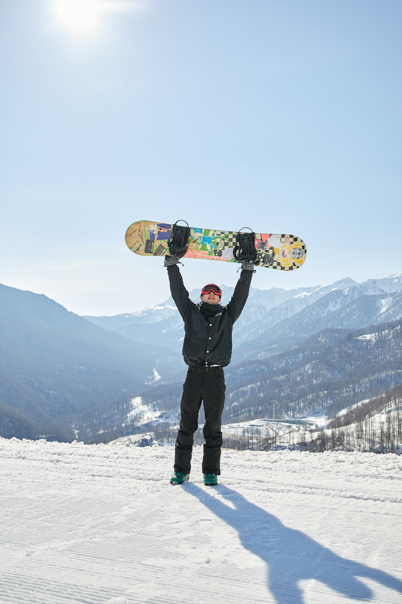 A Snowboarder Holding a Snowboard Up in the Air